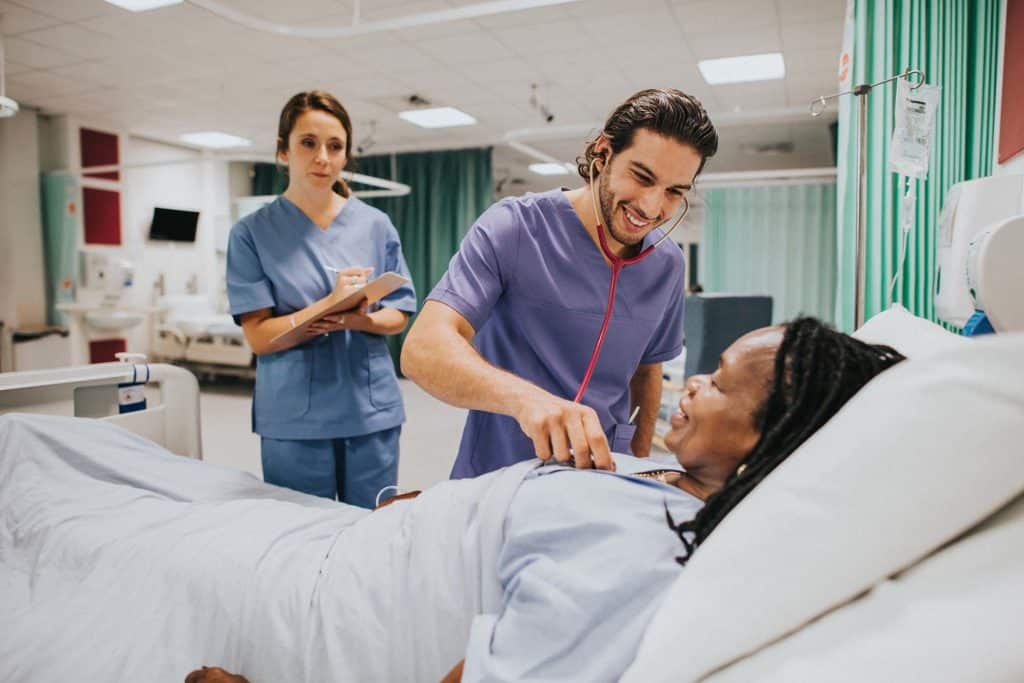 ER nurse checking on patient in hospital bed.